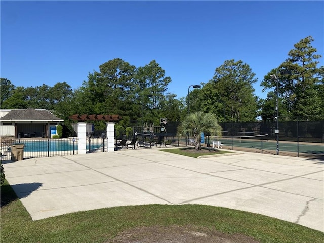 community pool featuring fence and a tennis court