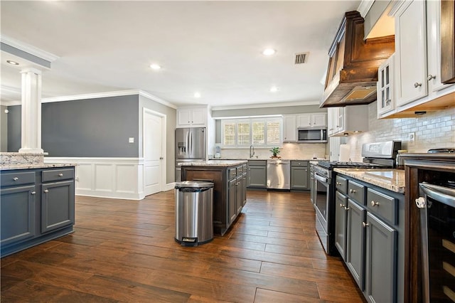 4072 Fenwick Loop, Mobile, AL 36619 - kitchen featuring appliances with stainless steel finishes, ornate columns, crown molding, light stone countertops, and dark wood finished floors