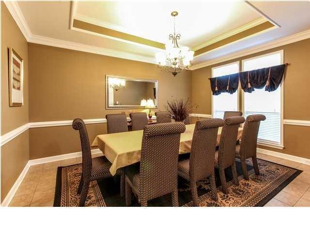 dining room with a chandelier, a raised ceiling, ornamental molding, and tile patterned floors