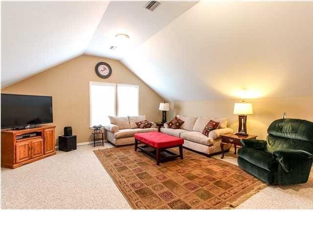 living area featuring carpet, visible vents, and vaulted ceiling