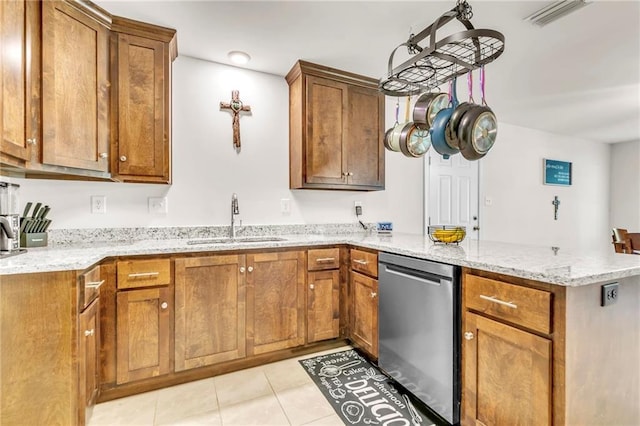 1933 Wildwood Pl, Mobile, AL 36609 - kitchen featuring brown cabinetry, a peninsula, light tile patterned flooring, a sink, and dishwasher