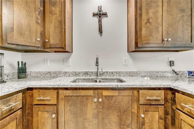 1933 Wildwood Pl, Mobile, AL 36609 - kitchen with brown cabinetry, a sink, and light stone countertops