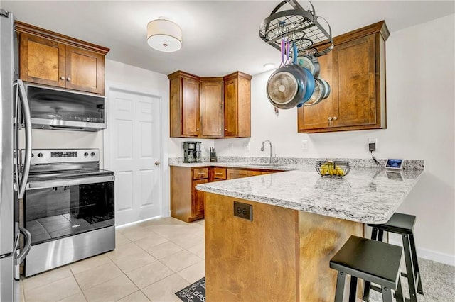 1933 Wildwood Pl, Mobile, AL 36609 - kitchen with brown cabinetry, a peninsula, a breakfast bar, a sink, and stainless steel appliances