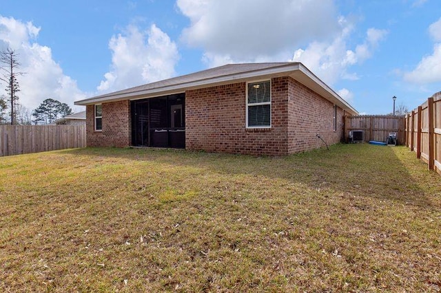 rear view of house featuring brick siding, a lawn, a fenced backyard, and central air condition unit