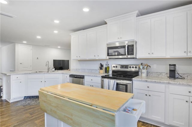 kitchen featuring a peninsula, appliances with stainless steel finishes, a sink, and white cabinetry