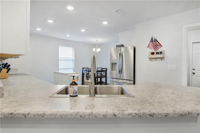 kitchen featuring recessed lighting, visible vents, white cabinets, a sink, and stainless steel fridge