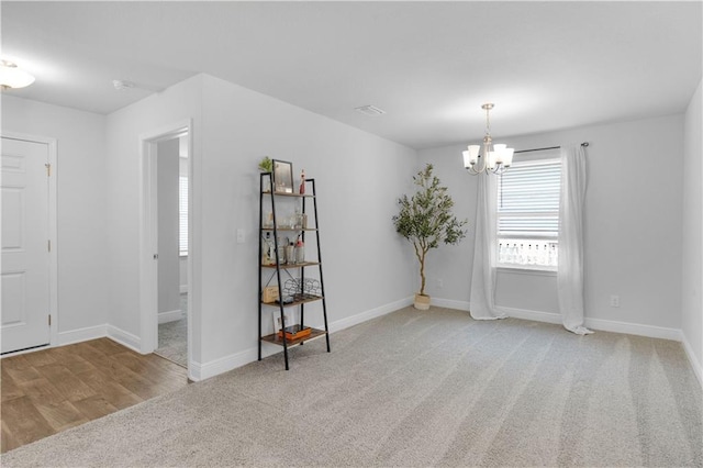 carpeted spare room with baseboards and a chandelier