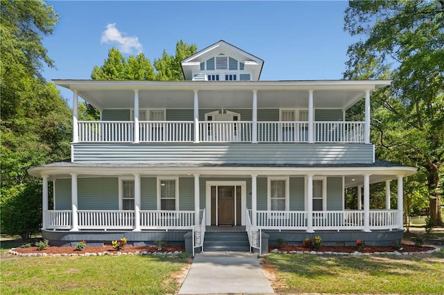 farmhouse inspired home with a balcony, a front yard, and covered porch