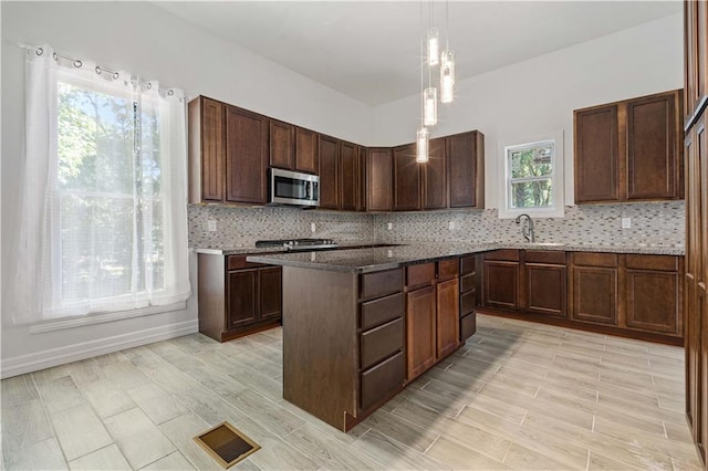 kitchen featuring sink, decorative backsplash, a healthy amount of sunlight, and dark brown cabinets