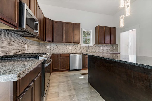 kitchen featuring stainless steel appliances, tasteful backsplash, sink, decorative light fixtures, and dark brown cabinets