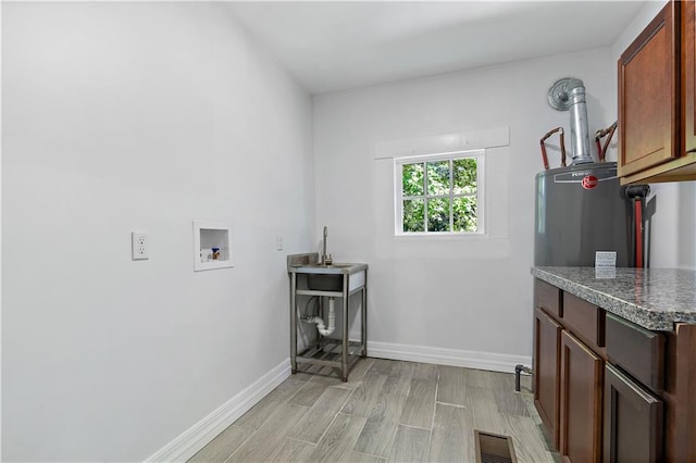 laundry area with light hardwood / wood-style flooring, washer hookup, gas water heater, and cabinets