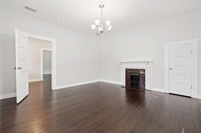 unfurnished living room with a chandelier, dark wood-type flooring, and a fireplace