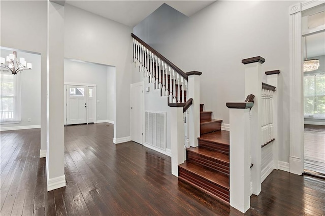 staircase with a high ceiling, a wealth of natural light, hardwood / wood-style flooring, and an inviting chandelier