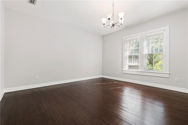 empty room with hardwood / wood-style flooring and an inviting chandelier