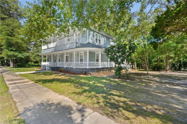 country-style home featuring a balcony, a front yard, and covered porch