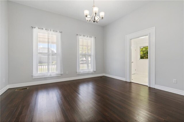 spare room featuring a notable chandelier and wood-type flooring