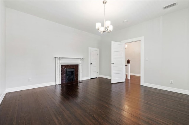 unfurnished living room with a notable chandelier, a high end fireplace, and dark hardwood / wood-style floors