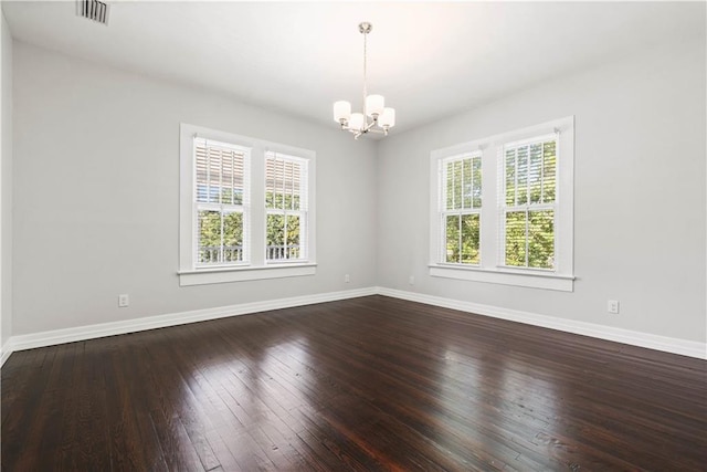 spare room with wood-type flooring and an inviting chandelier