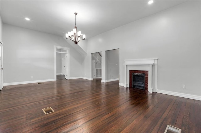 unfurnished living room with a fireplace, a notable chandelier, hardwood / wood-style floors, and a high ceiling