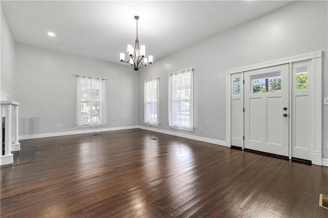 foyer entrance featuring a wealth of natural light, an inviting chandelier, and dark wood-type flooring