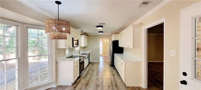 kitchen with white cabinetry, sink, light hardwood / wood-style flooring, pendant lighting, and appliances with stainless steel finishes