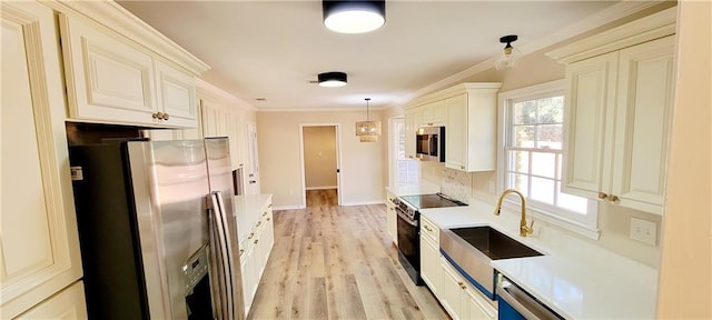 kitchen featuring pendant lighting, sink, light hardwood / wood-style flooring, ornamental molding, and stainless steel appliances