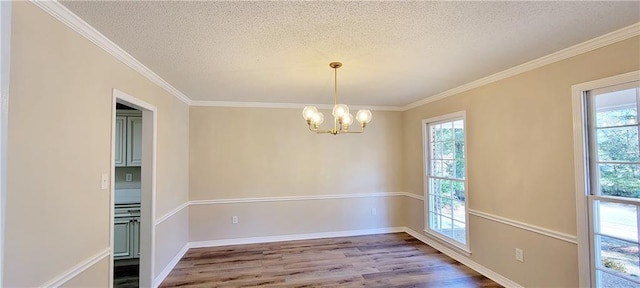 unfurnished room with hardwood / wood-style floors, ornamental molding, a textured ceiling, and a chandelier