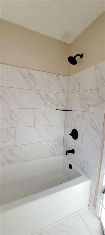 bathroom featuring a textured ceiling and tiled shower / bath combo