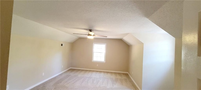 additional living space with a textured ceiling, light carpet, ceiling fan, and vaulted ceiling