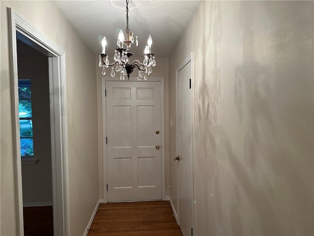 hall featuring dark wood-type flooring and an inviting chandelier