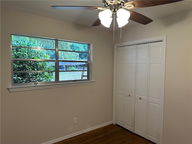 unfurnished bedroom featuring ceiling fan, dark hardwood / wood-style floors, and a closet