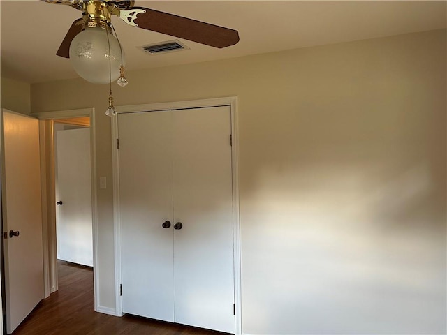 unfurnished bedroom with ceiling fan, dark hardwood / wood-style floors, and a closet