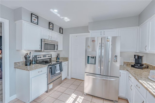 kitchen featuring light stone countertops, stainless steel appliances, white cabinetry, and light tile patterned floors