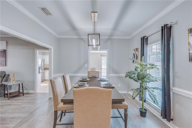 dining area featuring crown molding, a chandelier, and light hardwood / wood-style flooring