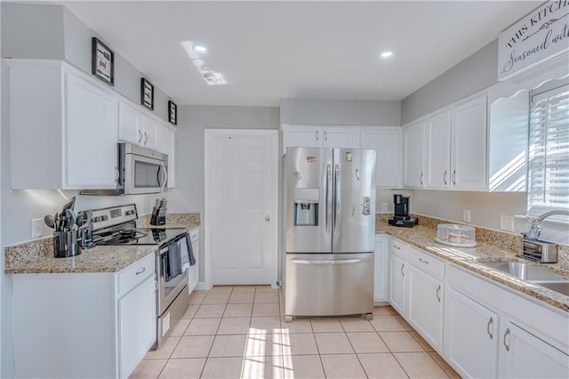 kitchen with sink, white cabinets, light tile patterned floors, and appliances with stainless steel finishes