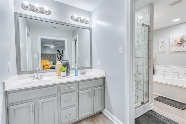 bathroom with ceiling fan, wood-type flooring, vanity, and plus walk in shower