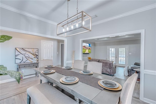 dining space with light hardwood / wood-style flooring, crown molding, french doors, and an inviting chandelier