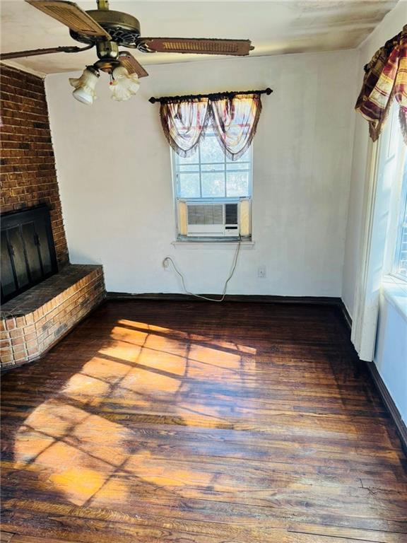 unfurnished living room with ceiling fan, dark hardwood / wood-style floors, cooling unit, and a fireplace