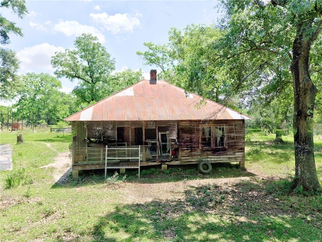 rear view of house featuring metal roof and a chimney