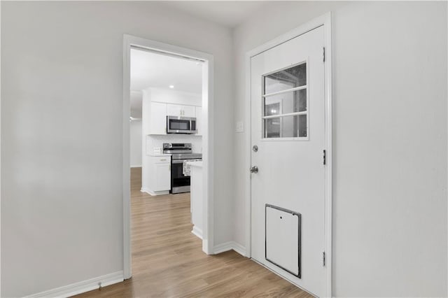 hall featuring baseboards and light wood finished floors