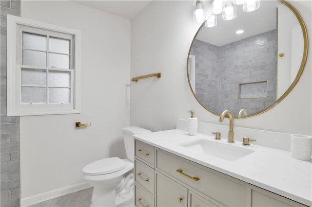 bathroom with toilet, vanity, and baseboards