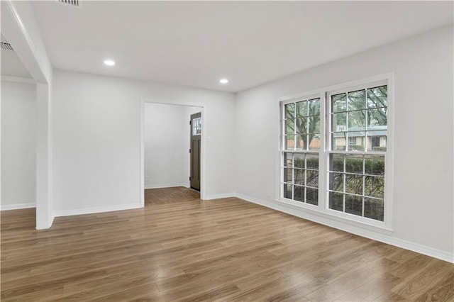 empty room with baseboards, wood finished floors, and recessed lighting