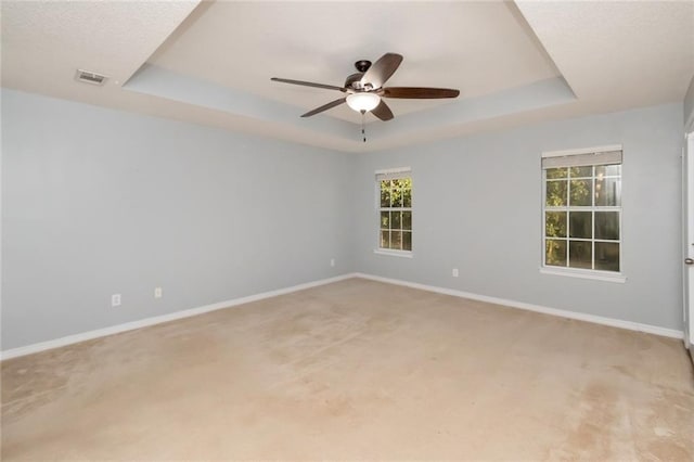 spare room with visible vents, baseboards, a raised ceiling, a ceiling fan, and carpet floors