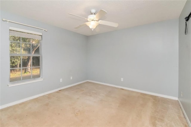 carpeted spare room with baseboards and a ceiling fan