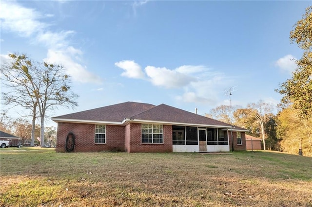 back of house featuring a shingled roof, a sunroom, brick siding, and a yard