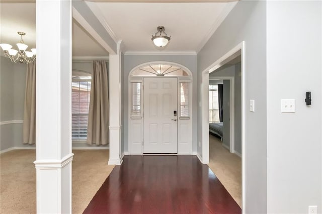 foyer with dark colored carpet, plenty of natural light, decorative columns, and crown molding