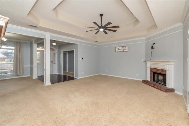 unfurnished living room featuring ceiling fan, a fireplace, a raised ceiling, and carpet