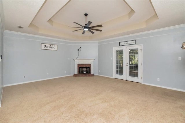 unfurnished living room with visible vents, a tray ceiling, carpet flooring, french doors, and a fireplace