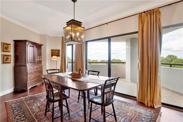 dining space with an inviting chandelier, crown molding, baseboards, and dark wood-style flooring