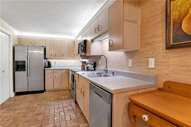 kitchen featuring light brown cabinets, a sink, stainless steel appliances, light countertops, and brick floor